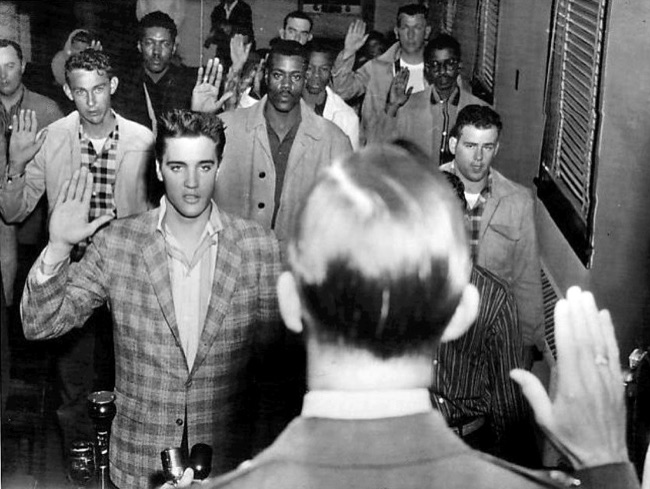 Elvis Presley, 23, stands among a group of young men with his right hand raised, taking the U.S. Army oath in March 1958